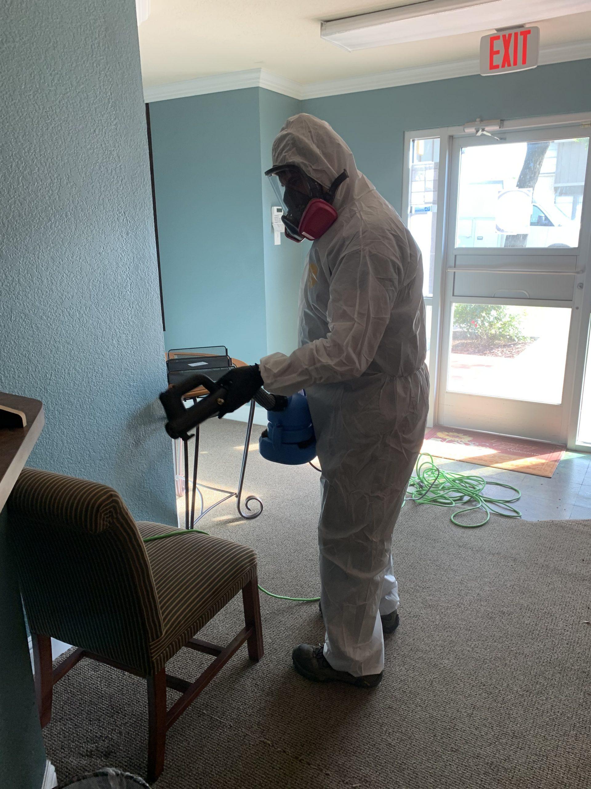 Technician applying odor removal treatment in a Dallas office lobby
